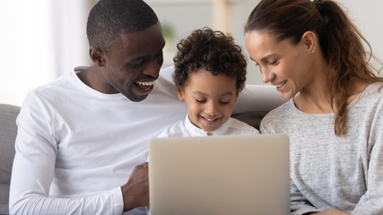 Happy African American family with little son using laptop together