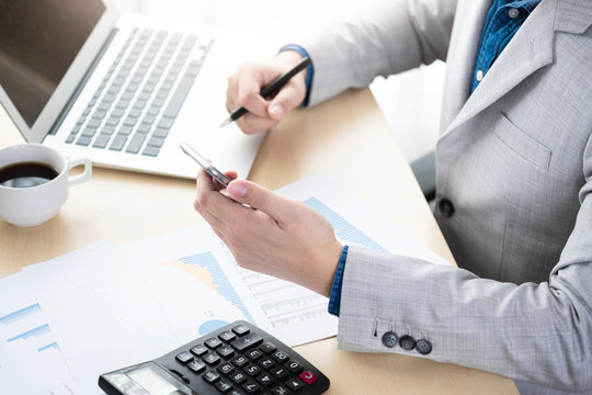 Businessman checking the business reports from the financial imformation from smartphone. Online business and economy concept.