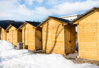 Small wooden shops standing in a row seen from the back with a metal roof and closed door.
