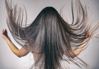 Back view of a brunette woman with a long straight hair.