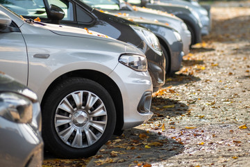 Modern cars parked on city street side in residential discrict. Shiny vehicles parked by the curb. Urban transportation infrastructure concept.