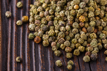 green peppercorns in wooden scoop on rustic background