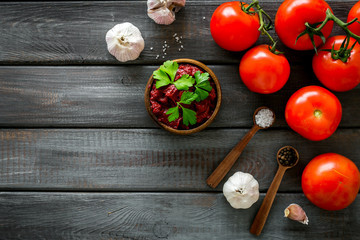 Homemade tomato sause near ingredients - garlic, spices - on dark wooden background top-down copy space