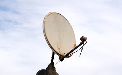 Satellite dish antenna over blue sky and roof background