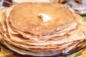 On the table, tea with pancakes, sour cream and jam for the Maslenitsa holiday, which is celebrated in Russia at the end of winter.