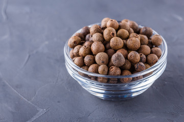 fresh spicy peppers allspice on a dark stone background