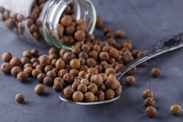 fresh spicy peppers allspice on a dark stone background
