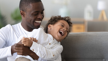 Happy African American father tickling laughing son close up