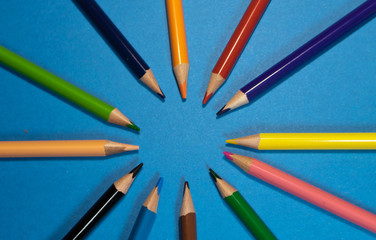 Fototapeta premium Frame of colored pencils on a blue background, top view. Space for text