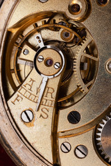 Close up of an authentic 100 hundred years old pocket watch mechanism cogs and wheels , golden, pendulum, jewels