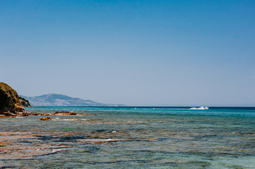 Peaceful beach with golden island and sand at sunset, sea with calm water, Greece