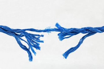 Fraying blue rope on white background showing concept of breaking strain, stress, tension, under...