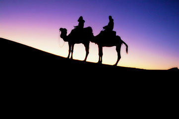 sunrise and people on camels in the desert