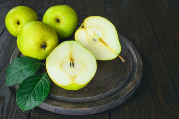 ripe large green pears lie on a cutting board on a wooden table. fresh ripe pears and pear halves close-up. background with large green pears.