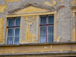 Crumbling wall on old historical building with windows in Brasov, Romania.