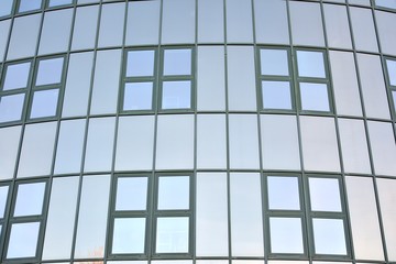 Glass transparent windows on the facade of a modern office or commercial building. Building in the center of a big city reflect the blue sky.