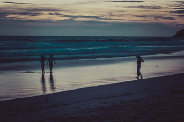 Fototapeta na wymiar people walking along the beach at sunset by the sea, beautiful evening landscape
