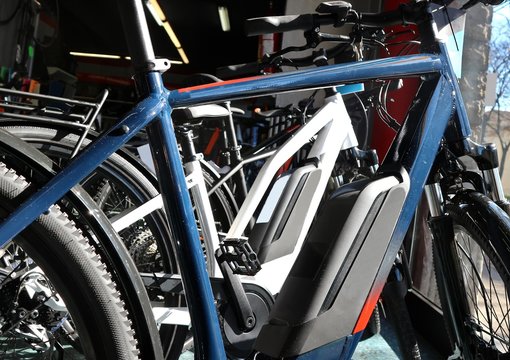 Brand New Electric Bicycles Or E Bike, With Their Batteries In The Foreground, In A Shop Window.