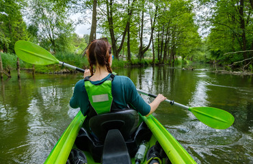 A woman kayaking down the river Wda in Kaszuby, Poland - obrazy, fototapety, plakaty