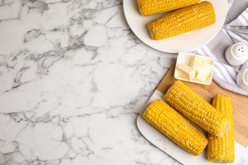 Delicious boiled corn served on white marble table, flat lay. Space for text