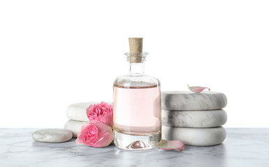 Fototapeta na wymiar Bottle of essential oil, flowers and stones on marble table