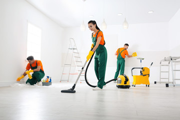 Team of professional janitors cleaning room after renovation