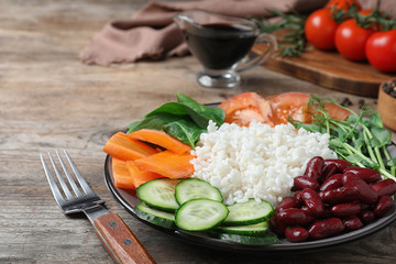 Tasty rice with beans and vegetables on wooden table, closeup