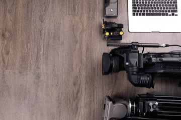 Flat lay composition with video camera and other equipment on wooden table. Space for text