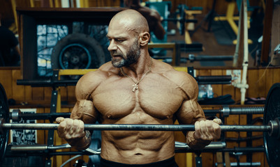 Fototapeta na wymiar Bodybuilder strong man pumping up biceps muscles.