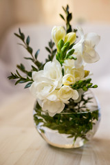 white freesia flowers in a spherical glass vase