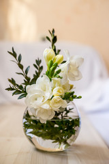 Naklejka na ściany i meble white freesia flowers in a spherical glass vase