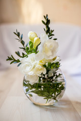 white freesia flowers in a spherical glass vase
