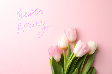 Words HELLO SPRING and fresh tulip flowers on pink background, flat lay