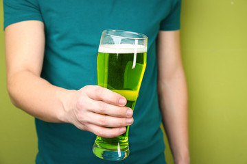 Man with green beer on color background, closeup. St. Patrick's Day celebration