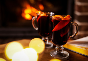 Tasty mulled wine, festive lights and blurred fireplace on background