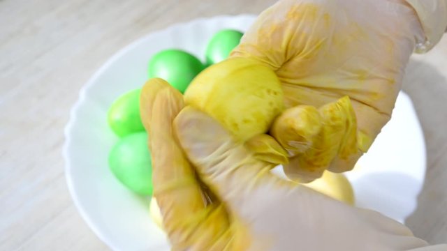 Easter celebration. Girl in gloves paints easter eggs in yellow. Cooking for the holiday. Easter traditions.