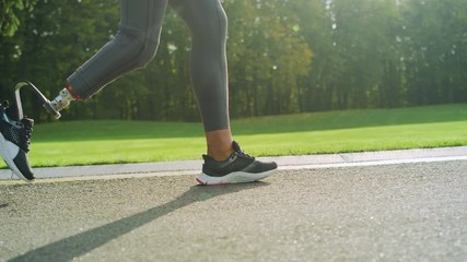 Disabled woman in sports shoes running on road. Girl feet training outdoors - Powered by Adobe
