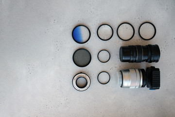 Two lenses and filters to them, adapter rings and a box with flash drives on grey backgrond. Flat lay composition with equipment for photographer
