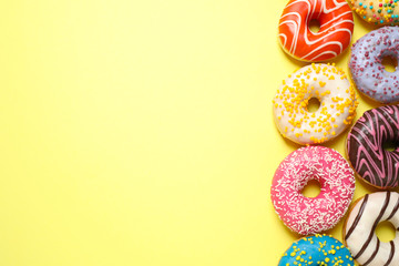 Fototapeta na wymiar Delicious glazed donuts on yellow background, flat lay. Space for text