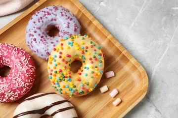 Yummy donuts with sprinkles on marble table, top view