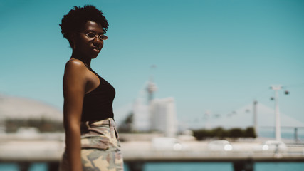 True tilt-shift shot of a charming African female in a sunglasses on bright springtime day with a selective focus on her have and a copy space place on the right for an ad text message or your logo