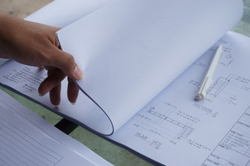 A man's hand opening a large white paper, Drawing the construction project.