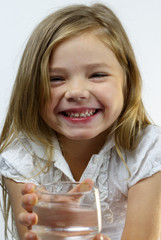 Portrait of a smiling girl stretching a glass of water.