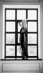 blonde girl in a black negligee by the window