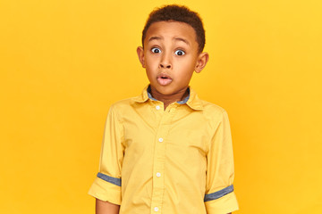 Handsome funny dark skinned shoolboy popping eyes out and exclaiming Are you kidding me? Shocked...