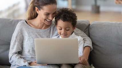 Smiling mother with African American son using laptop at home