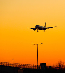Fototapeta na wymiar An airliner coming in to land at sunset silhouetted against a background of orange sky