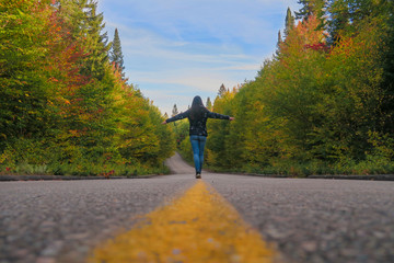 Adventure: woman walking on a canadian road at fall