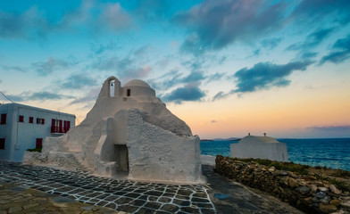 Traditional white greek church near the sea on Mykonos island at sunset