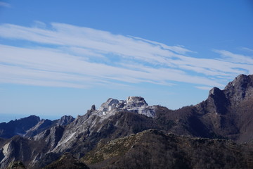 Fototapeta na wymiar View of the Apuan Alps with a peak cut due to the extraction of white marble